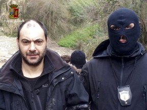 A police officer escorts fugitive Giuseppe Ferraro in this handout picture released by the Italian Police on January 29, 2016. Italian police arrested two fugitive mobsters on Friday in a bunker built on a steep slope and surrounded by dense brush where they were hiding out to avoid prosecution for mafia association, extortion and murder. (REUTERS/Italian Police/Handout via Reuters)
