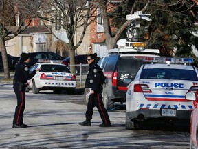 Police officers speak on Milldock Dr. in Scarborough where a man’s body was found on the roadway with serious injuries. (Michael Peake/Toronto Sun)