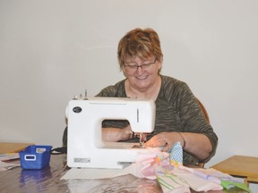 Anne Ingram sews together squares of fabric for a quilt during the Zebra Quilting Group’s gathering on Jan, 22. - Photo by Marcia Love