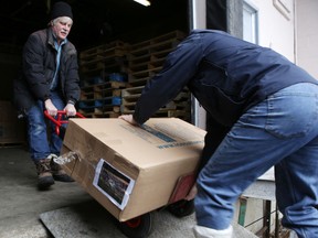 David Dossett and Duncan Walker load an artwork encased within a 135-kilogram (300 pound) block of ice into a truck at Quattrocchi's Specialty Foods on Friday. The artworks are to be displayed at locations around the city as part of the Froid'art — Art on Ice. (Elliot Ferguson/The Whig-Standard)