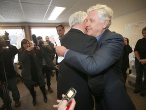 Justice Minister Gord Mackintosh (right) hugs Premier Greg Selinger after announcing he won't seek re-election.