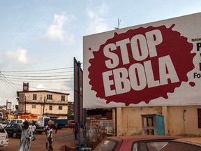 FILE- In this file photo taken on Friday, Jan. 15, 2016, people pass a banner reading 'STOP EBOLA' forming part of Sierra Leone's Ebola free campaign in the city of Freetown, Sierra Leone. A second case of Ebola emerged Thursday Jan. 21, 2016 in Sierra Leone after health officials thought the epidemic was over, with a close relative of the first victim testing positive for the virus that has killed more than 11,000 people, authorities said.  (AP Photo/Aurelie Marrier d'Unienville,File)