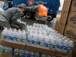 Members of the Michigan National Guard load bottled water at a fire station, Thursday, Jan. 28, 2016 in Flint, Mich. The Michigan Legislature voted Thursday to direct another $28 million to address Flint's water emergency, allocating money for bottled water, medical assessments and other costs in the city struggling with a lead-contaminated supply. (AP Photo/Carlos Osorio)