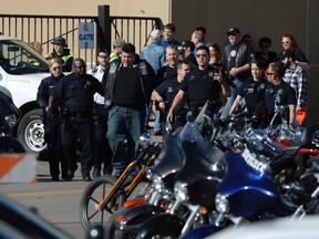 Denver Police escort a man in handcuffs away from the National Western Complex, Saturday, Jan. 30, 2016, in Denver. Denver police say multiple people were injured in a deadly stabbing and shooting at The Colorado Motorcycle Expo. (Andy Cross/The Denver Post via AP)