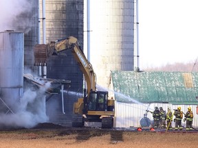 Firefighters spray water onto a barn fire as an operator uses a piece of heavy machinery to open a hole in the roof at Prikken Farm Ltd. on Sunset Drive south of Highway 401 in London on Monday. About 85 dairy cows were killed and several buildings razed by the fire, which caused an estimated $1.5 million in damage.  The fire is the latest in a succession of barn blazes in Ontario, which collectively have claimed thousands of horses and pigs, and caused millions of dollars in damage. (CRAIG GLOVER, The London Free Press)