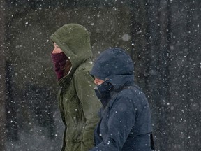 People walk as snow falls during the first winter storm of the year in Ottawa on Tuesday, Dec. 29, 2015. Environment Canada is forecasting up to 20 centimetres of snow for the Ottawa region. THE CANADIAN PRESS/Justin Tang