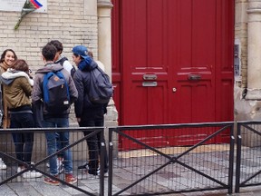 French high school students  wait in front of Lycee Victor Hugo  in Paris, Tuesday Feb, 2 2016.  French high schools say students should be allowed to smoke on school grounds to stop them becoming terrorist targets when they gather for cigarette breaks outside.  (AP Photo/Jacques Brinon)