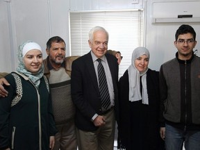 Immigration Minister John McCallum, centre, poses for a photograph with a Syrian family to be resettled in Canada, Dec. 20, 2015, at the UN refugee agency building in Amman, Jordan. (THE CANADIAN PRESS/AP/Sam McNeil)