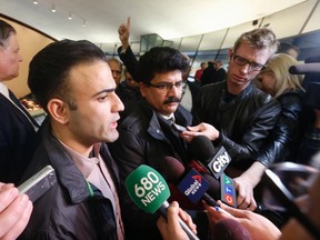 Sajid Mughal, president of the Taxi Workers Association of Ontario (middle) and Sam Moini, Toronto Taxi Alliance spokesman (left) speak to the media after a large group of Toronto cabbies were removed from city hall Wednesday, February 3, 2016. (Jack Boland/Toronto Sun)