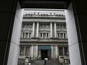 A man holding an umbrella walks in front of the Bank of Japan headquarters in Tokyo, Japan, January 29, 2016. The Bank of Japan ramped up its aggressive stimulus campaign on Friday, adding negative interest rates on central banks deposits to its massive asset-buying program, stunning financial markets that expected no action or a moderate increase in asset purchases. REUTERS/Yuya Shino