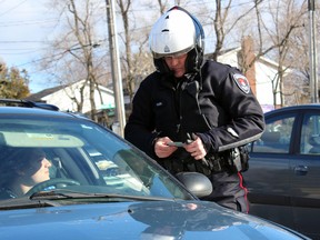 Const. Rick Hough, traffic enforcement officer and collision reconstructionist with Kingston Police, stops a vehicle after observing a passenger not wearing a seatbelt in Kingston on Thursday. (Steph Crosier/The Whig-Standard)