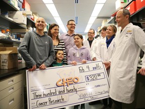 Elias Hawa, 12, left, who has brain cancer, presented a cheque to Dr David Stojdl, right, a CHEO cancer researcher in the hopes of finding a cure. 
(Left to right) Elias Hawa, Mom Manal Hawa, little brother George Hawa, Dad Raja Hawa, sister Reina Hawa, Scientist Charles Lefebvre, Scientist Stephanie Swift, Scientist Kristina Allan and Dr David Stojdl.