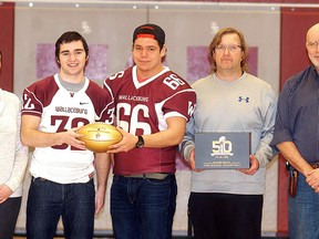 Wallaceburg District Secondary School athletic director Janine Day, left, football players Jacob Broad and Quinn Williams, football coach Rob MacLachlan and principal Rob Lee show the golden football received from the NFL to honour the Super Bowl participation of WDSS graduate Shaun Suisham. (DAVID GOUGH/Postmedia Network)