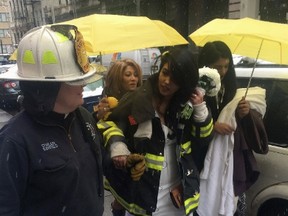 Bride-to-be Nesh Pillay, 25, is assisted by New York City firefighter Chaplain Ann Kansfield after a crane collapsed near the beauty salon where she was having her hair done in downtown Manhattan in New York, on Feb. 5, 2016. (REUTERS/Gina Cherelus)