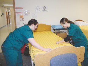 Healthcare aid program students Kaylyn Zlingle and Desiree Hoffman make a bed in the lab at NorQuest College’s Stony Plain campus. - photo by Marcia Love