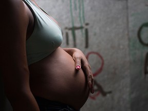 In this Jan. 29, 2016 photo, a pregnant woman stands in the entrance of her stilt home with her hand on her baby bump, at a slum in Recife, Brazil. (AP Photo/Felipe Dana)
