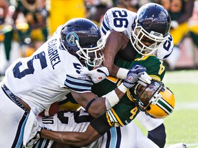 Edmonton’s Adarius Bowman (4) is tackled hard by Toronto’s Jermaine Gabriel (5) and Branden Smith (26) during CFL play at Commonwealth Stadium in Edmonton on Saturday, Aug. 23, 2014. (Postmedia Network file photo)