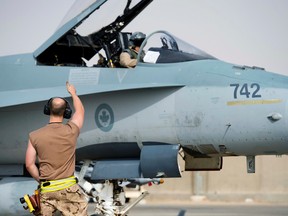 Royal Canadian Air Force technician gives a thumbs to a CF-18 Hornet pilot from Cold Lake, Alta., as he heads out on a mission from Camp Patrice Vincent, Kuwait during Operation IMPACT on June 11, 2015. (Canadian Forces/Combat Camera/DND)