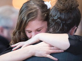 Two unidentified family members hug before the joint funeral service for Yves Carrier, his wife Gladys Chamberland, their adult son Charles-Elie Carrier and Yves' adult daughter, Maude Carrier, as well as their friend Louis Chabot, who died in a terrorist attack in Burkina Faso in January, Saturday, February 6, 2016 in Quebec City. THE CANADIAN PRESS/Jacques Boissinot