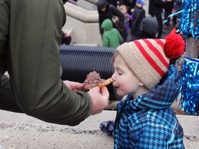 Ernie Leiliunas let his son Duncan try a Beavertail at FebFest in Springer Market Square in Kingston, Ont. on Saturday February 6, 2016. Steph Crosier/Kingston Whig-Standard/Postmedia Network