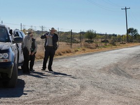 In this Saturday, Feb. 6, 2016 photo, Uvalde County Sheriffs Deputies guard the intersection to a neighborhood several miles outside of Uvalde, Texas. A 19-year-old killed his mother and two neighbors before turning his gun on himself in a shooting that brought SWAT and various emergency vehicles to a rural area, authorities said Sunday, Feb. 7. (Kin Man Hui, San Antonio Express-News via AP)