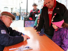 Hockey legend Ron Ellis signs an autograph for six-year-old Emma and her father Shaun Mounsteven of Carrying Place at FebFest in Springer Market Square in Kingston, Ont. on Saturday February 6, 2016. Steph Crosier/Kingston Whig-Standard/Postmedia Network