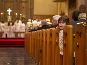 Zephyr Fleming, 2 1/2, peers from between the pews during the final service at St. Matthias Anglican Church on Sunday.