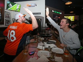 Ray Timlick (left) and Kevin Turner high-five while watching Denver beat Carolina to win Super Bowl 50 at the Boston Pizza on St. James Street in Winnipeg on Sun., Feb. 7, 2016. Kevin King/Winnipeg Sun/Postmedia Network