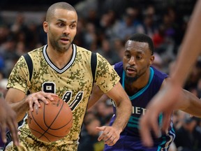 San Antonio Spurs guard Tony Parker, center, of France, evades Charlotte Hornets guard Kemba Walker during the second half of an NBA basketball game, Saturday, Nov. 7, 2015, in San Antonio. San Antonio won 114-94. (AP Photo/Darren Abate)