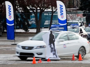 Professional race car driver Parker Thompson, 17, hits a cardboard cutout of a cyclist while trying to text and drive during a Province of Alberta press conference on distracted driving, at the Edmonton Expo Centre, in Edmonton Alta. on Monday Feb. 8, 2016. Photo by David Bloom