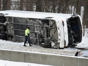 A Connecticut State Police officer investigates an overturned casino-bound tour bus on I-95 North near exit 61 in Madison, Conn., Monday, Feb. 8, 2016. (Arnold Gold/New Haven Register via AP)