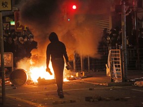 A protester holds bricks in front of fires in Mong Kok district of Hong Kong, Tuesday, Feb. 9, 2016. The unrest started when authorities tried to prevent unlicensed food vendors from operating street stalls on Monday night in the crowded Kowloon neighborhood of Hong Kong. Overnight and into the early morning hours Tuesday, activists backing the hawkers engaged in running battles with police.  (AP Photo/Vincent Yu)