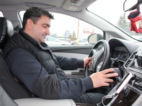 Uber driver Emil Akhmedov checks his smartphone ready to answer texts from riders. (Postmedia Network file photo)