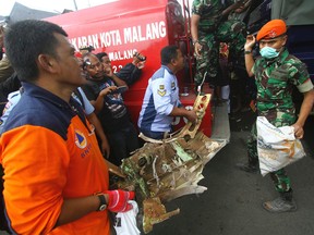 Rescuers carry a part of an Indonesian Air Force plane which crashed into a house in Malang, East Java, Indonesia, on Feb. 10, 2016. The Brazilian-made Embraer EMB 314 Super Tucano plane crashed during a routine training flight. (AP Photo)