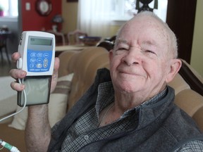 Garth Scott, at his home in Kingston, holds the Duodopa pump that injects medication directly into his small intestine to control the symptoms of his Parkinson's Disease. The procedure is relatively new to Canada. (Michael Lea/The Whig-Standard)