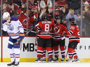 The New Jersey Devils celebrate a goal by New Jersey Devils center Adam Henrique during the first period at Prudential Center as Oilers winger Benoit Pouliot skates away.