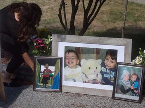 Family friend Nissy Koye, left, places flowers beside photographs of late brothers Alan and Ghalib Kurdi and their mother Rehanna displayed outside the home of their aunt Tima Kurdi, in Coquitlam, B.C., on Friday, September 4, 2015. Two alleged people-smugglers are on trial in Turkey accused of causing the death of 3-year-old Syrian migrant boy Alan Kurdi and four other people. THE CANADIAN PRESS/Darryl Dyck