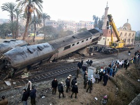 People gather at the site of a train derailment near Beni Suef, Egypt, Thursday, Feb. 11, 2016. Dozens of people were injured as it was traveling north toward Cairo. (AP Photo/Samer Abdallah)