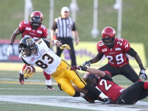 Hamilton Tiger-Cats receiver Andy Fantuz stretches for yardage as he’s brought down by Calgary Stampeders defender Juwan Simpson at McMahon Stadium in Calgary Friday June 26, 2015. (Jim Wells/Calgary Sun/Postmedia Network)