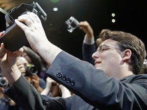 In this June 11, 2015 file photo, Oculus founder Palmer Luckey holds up the new Oculus Rift virtual reality headset for photographers following a news conference, in San Francisco. (AP Photo/Eric Risberg, File)