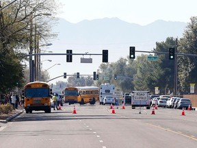 Buses make their way to bring parents waiting to reunite with their children, Friday, Feb. 12, 2016, in Glendale, Ariz., after two teens were shot Friday at Independence High School in the Phoenix suburb. (AP Photo/Matt York)
