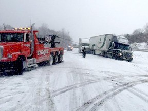 A tow truck pulls a tractor-trailer out of the ditch on the eastbound lanes of Highway 401, near Gananoque, on Friday morning, Feb. 12, 2016. (OPP TWITTER PHOTO)