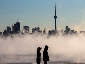 Steam rises as people look out on Lake Ontario in front of the skyline during extreme cold weather in Toronto on Saturday, Feb. 13, 2016. (THE CANADIAN PRESS/Mark Blinch)