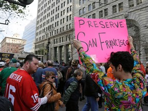 Shane Zaldivar holds up a sign as crowds jam Market Street trying to enter Super Bowl City Saturday, Feb. 6, 2016, in San Francisco. Zaldivar said the sign was a protest against the lack of affordable housing disappearing in San Francisco. (AP Photo/Eric Risberg)