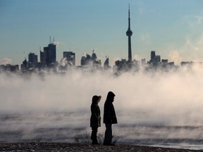 Steam rises as people look out on Lake Ontario in front of the skyline during extreme cold weather in Toronto on Saturday. (Mark Blinch/THE CANADIAN PRESS)