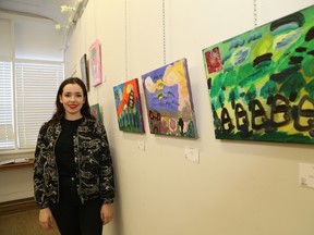 Tessa McDougall, of Artists on Elgin in Sudbury, Ont., stands next to a selection of art featured in The Story of Us: a narrative painting collective by NISA. John Lappa/Sudbury Star/Postmedia Network