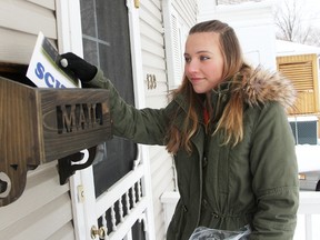 SCITS student Karly Lankin, 15, poses before dropping a flyer in a Mitton Village home's mailbox Monday. The Grade 10 student was one of about 30 volunteers spreading the word about efforts to save her school from closure. (Tyler Kula, The Observer)