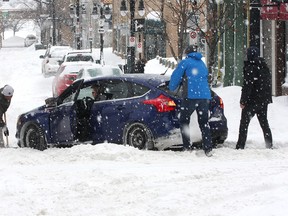 Some good Samaritans help a driver get their car down Princess Street at King Street during a heavy snowstorm in Kingston on Tuesday Feb. 16 2016. Environment Canada was predicting about 30 centimetres to fall in the area on Tuesday. Ian MacAlpine /The Whig-Standard/Postmedia Network