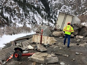 In this photo provided by the Colorado Department of Transportation a highway worker examines debris from a rock slide on Interstate 70 in Glenwood Canyon in western Colorado on Tuesday, Feb. 16, 2016. The rocks damaged the tractor-trailer rig visible in the background, but state officials said no one was injured. The interstate was closed in both directions while the canyon walls were inspected and the damage was repaired. (Colorado Department of Transportation via AP) MANDATORY CREDIT