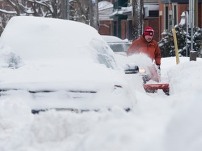 Guy Dupuis uses his snowblower Wednesday, February 17, 2016 to clear the sidewalk in front of his neighbour's following a winter storm in Ottawa. During the storm record snowfall was measured for the area. THE CANADIAN PRESS/Adrian Wyld